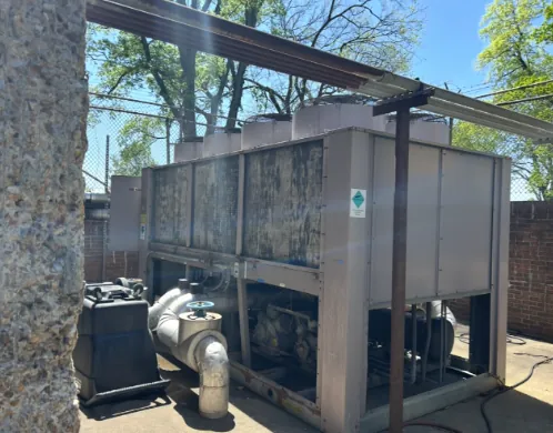 Air-cooled chiller with condenser fans on top and chilled-water piping and a pump at its base