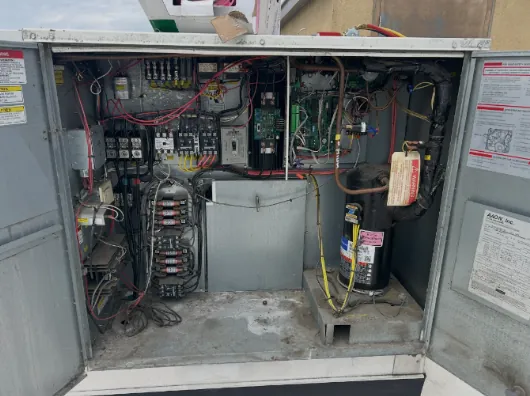 Open package unit showing contactors, a control board and a scroll compressor in one compartment