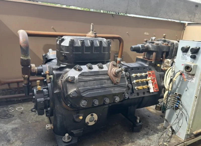 Large semi-hermetic reciprocating compressor with its terminal box and suction line inside a rooftop unit