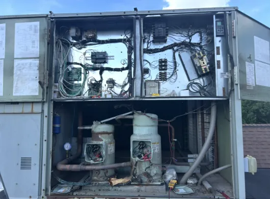Two scroll compressors below the open control section of a rooftop unit