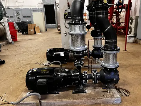 Pair of end-suction hydronic pumps with suction fittings on a mechanical room floor